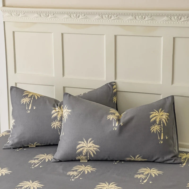 Ensemble de coussin décoratif avec motif de palmiers dorés sur fond gris, disposé sur un mur boisé orné de moulures sculptées.