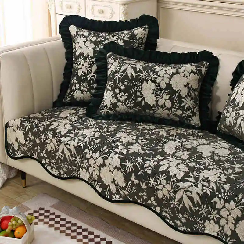 Un canapé vintage avec des coussins décoratifs noirs et blancs imprimés de fleurs et motifs floraux élégants, offrant un style classique et raffiné dans cette pièce élégante.