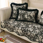 Un canapé vintage avec des coussins décoratifs noirs et blancs imprimés de fleurs et motifs floraux élégants, offrant un style classique et raffiné dans cette pièce élégante.