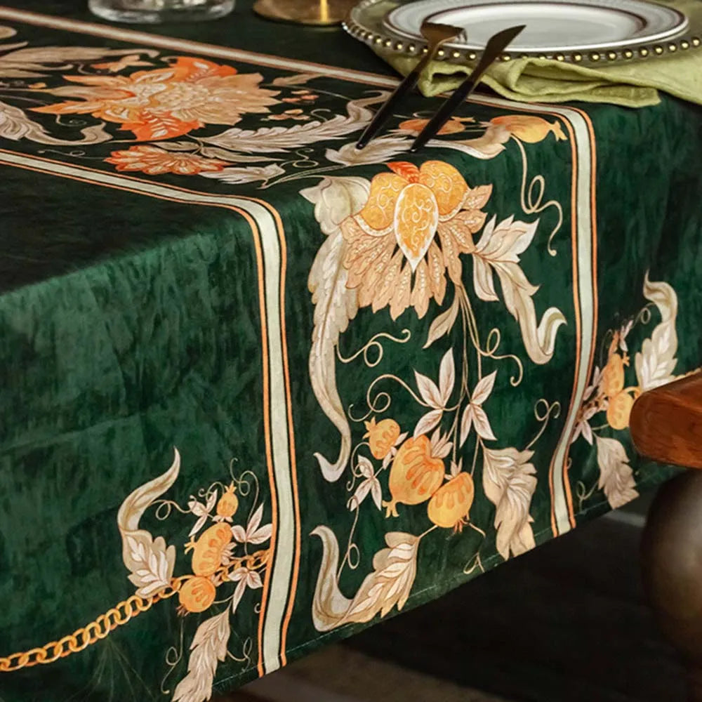 Une nappe de table en velours vert foncé, ornée de magnifiques motifs floraux en tons de beige, de blanc et d'orange, créant une ambiance élégante et raffinée.