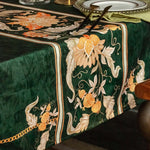 Une nappe de table en velours vert foncé, ornée de magnifiques motifs floraux en tons de beige, de blanc et d'orange, créant une ambiance élégante et raffinée.