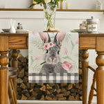 Un lapin gris mignon portant une couronne de fleurs roses sur un fond floral et à carreaux.