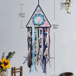 Beau capteur de rêves triangulaire décoré de perles, de plumes et de motifs colorés, suspendu dans un style bohème.