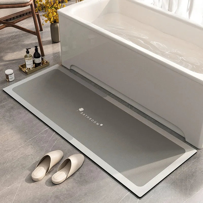 Tapis de bain gris élégant et épuré posé sur un sol carrelé près d'une baignoire blanche et d'accessoires de salle de bain.