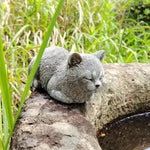 ornement zen statue chat gris allongé texture pierreuse jardin fleurs plantes