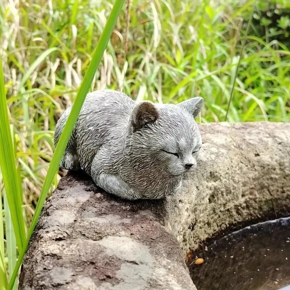 ornement zen statue chat gris allongé texture pierreuse jardin fleurs plantes