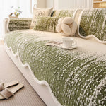 Un plaid douillet et confortable avec une texture texturée en vert et blanc, posé sur un canapé blanc, avec un coussin en forme de noeud et une tasse posée près, créant une ambiance cocooning et accueillante.