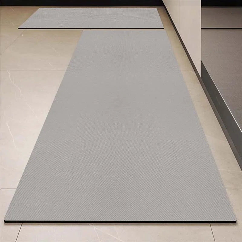 Tapis rectangulaire gris clair posé sur un sol carrelé blanc et noir.