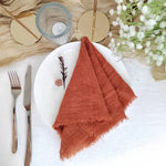 La nappe blanche avec des accessoires et un linge de table orange crée une ambiance chaleureuse et élégante pour ce service de table.