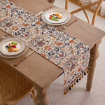 Un chemin de table fleuri aux couleurs automnales s'étend sur une table en bois, accueillant des plats garnis de fruits frais et délicieux.