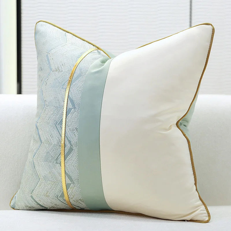 Un coussin décoratif blanc avec des motifs géométriques bleus et dorés, placé sur un canapé confortable.