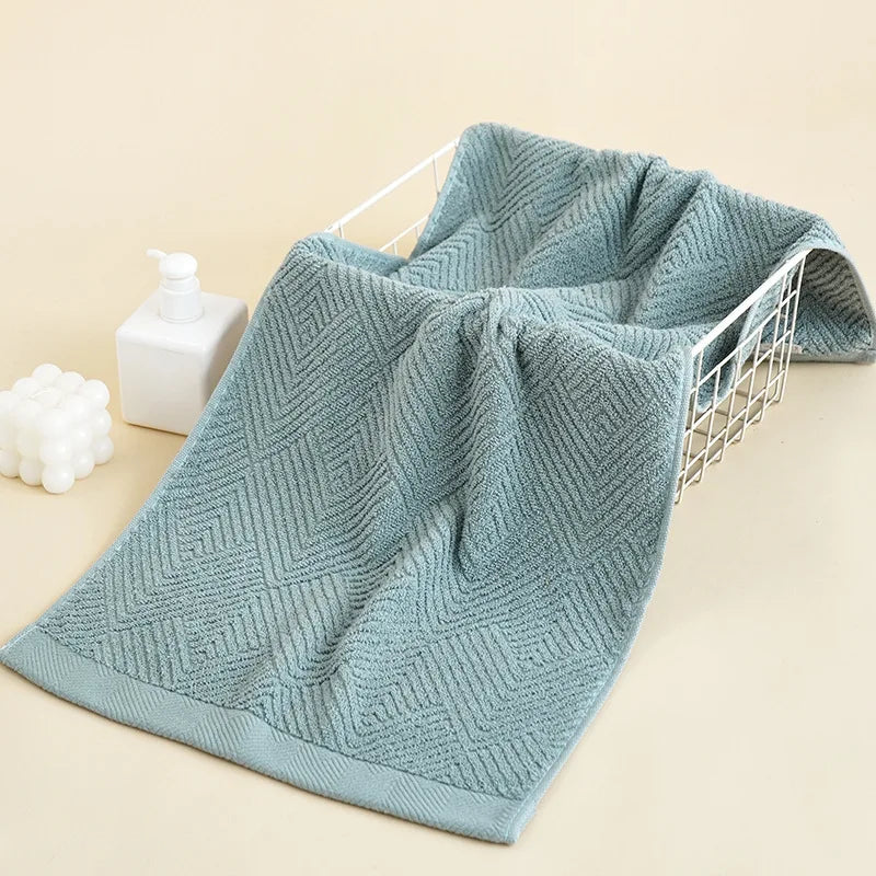 Une serviette de bain en maille bleu-vert, avec un motif géométrique texturé, offrant une touche de fraîcheur et de style dans la salle de bain.