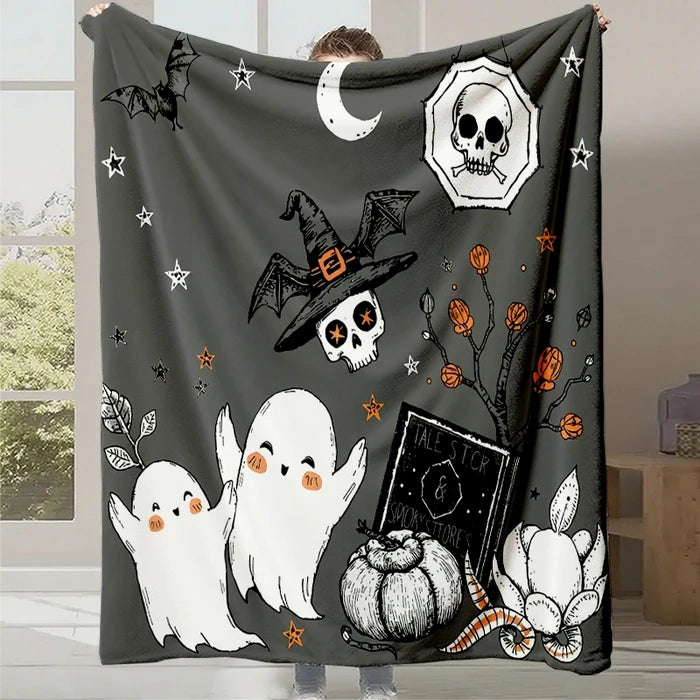 Couverture en polaire conçue pour l'Halloween, avec des motifs de chauves-souris, de lune, de crânes, de fantômes et de citrouilles sur un fond noir.
