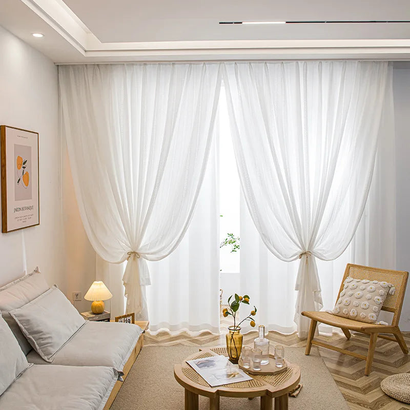 Salon cosy avec voilages blancs noués laissant passer la lumière naturelle.