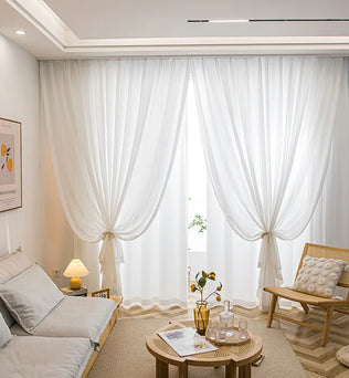 Salon cosy avec voilages blancs noués laissant passer la lumière naturelle.