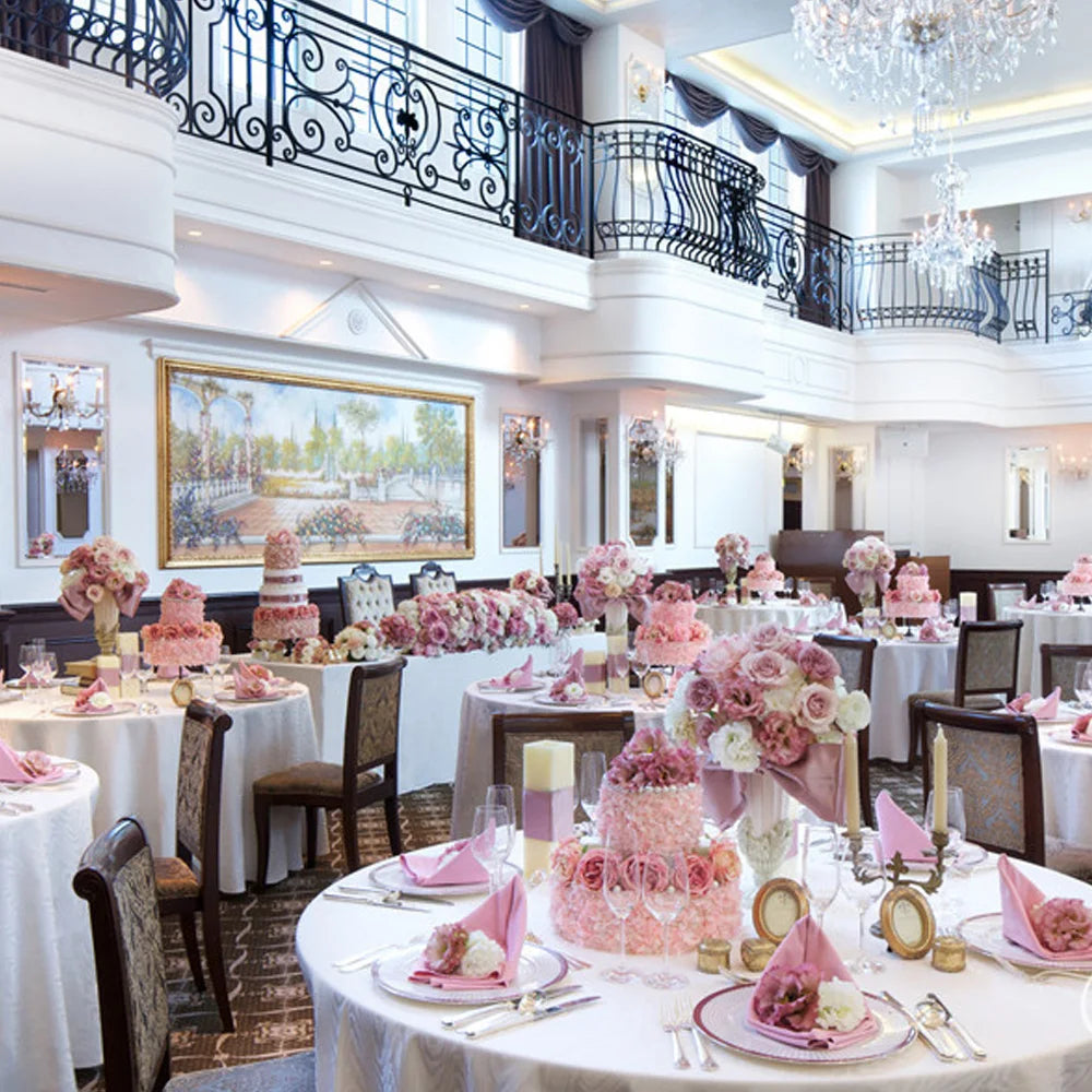 Une salle de réception élégante, décorée avec des arrangements floraux roses et des lustres étincelants, offrant un cadre luxueux pour un événement spécial.