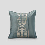 Coussin décoratif en satin de couleur vert grisé avec un motif géométrique élégant.
