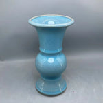 Un vase turquoise élégant avec un motif distinctif et une forme unique, créant une pièce décorative d'une grande beauté.