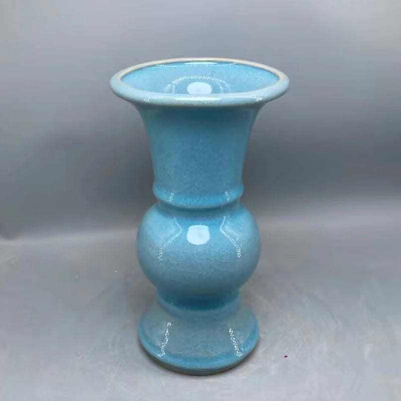 Un vase turquoise élégant avec un motif distinctif et une forme unique, créant une pièce décorative d'une grande beauté.