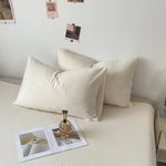 L'image montre un lit avec deux oreillers blancs confortables et quelques polaroids accrochés au mur, créant une atmosphère apaisante et intime.