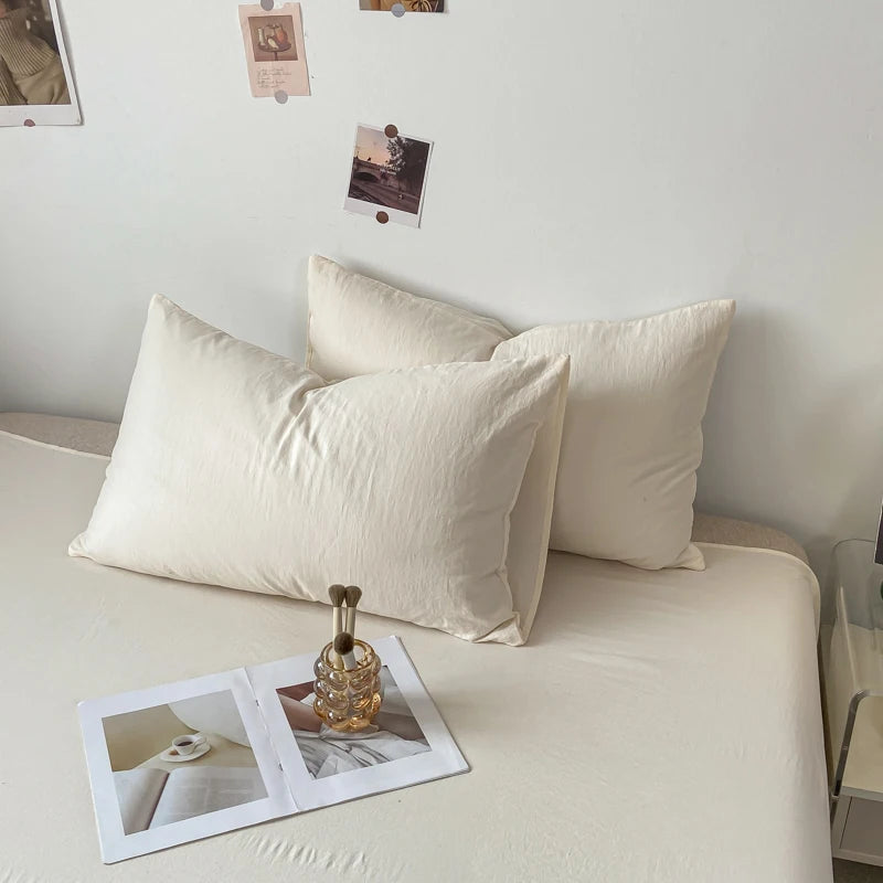 L'image montre un lit avec deux oreillers blancs confortables et quelques polaroids accrochés au mur, créant une atmosphère apaisante et intime.