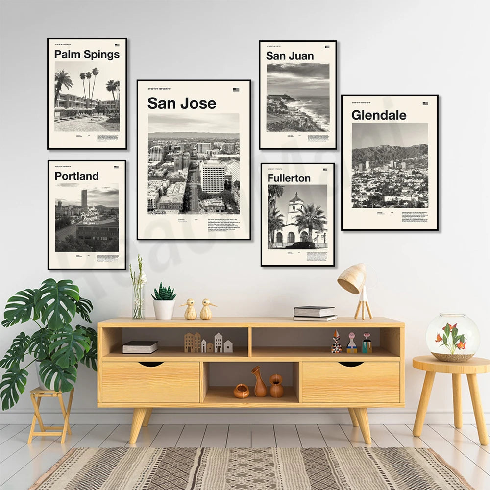 Une série d'affiches évoquant différentes villes américaines, encadrées sur un mur, avec un meuble en bois clair et des plantes d'intérieur.