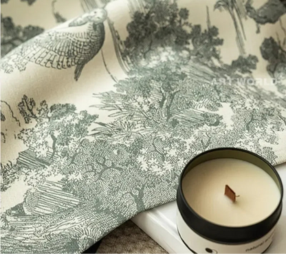Gros plan sur le tissu du rideau à motifs forestiers avec une bougie posée à côté, mettant en avant les détails du dessin.