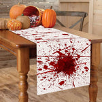 Table de ferme en bois rustique avec des citrouilles et une nappe aux motifs de gouttes de sang, créant une ambiance effrayante parfaite pour une décoration d'Halloween.
