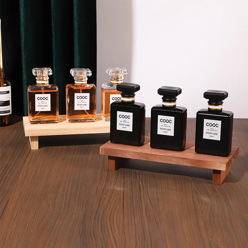 présentoir bois étagères parfum flacons transparents figurines décoratives diffuseur ambré rideau vert table festive