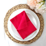 Serviette en feutre rouge posée sur une assiette blanche entourée d'un napperon tressé.