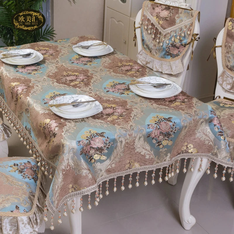 Un élégant et luxueux ensemble de table comprenant une nappe de style vintage avec des motifs floraux et des bordures décoratives, accompagné de chaises de design raffiné, créant une ambiance chaleureuse et accueillante.