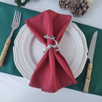 Élégante décoration de table avec serviette rouge festive et décorations de Noël en arrière-plan.