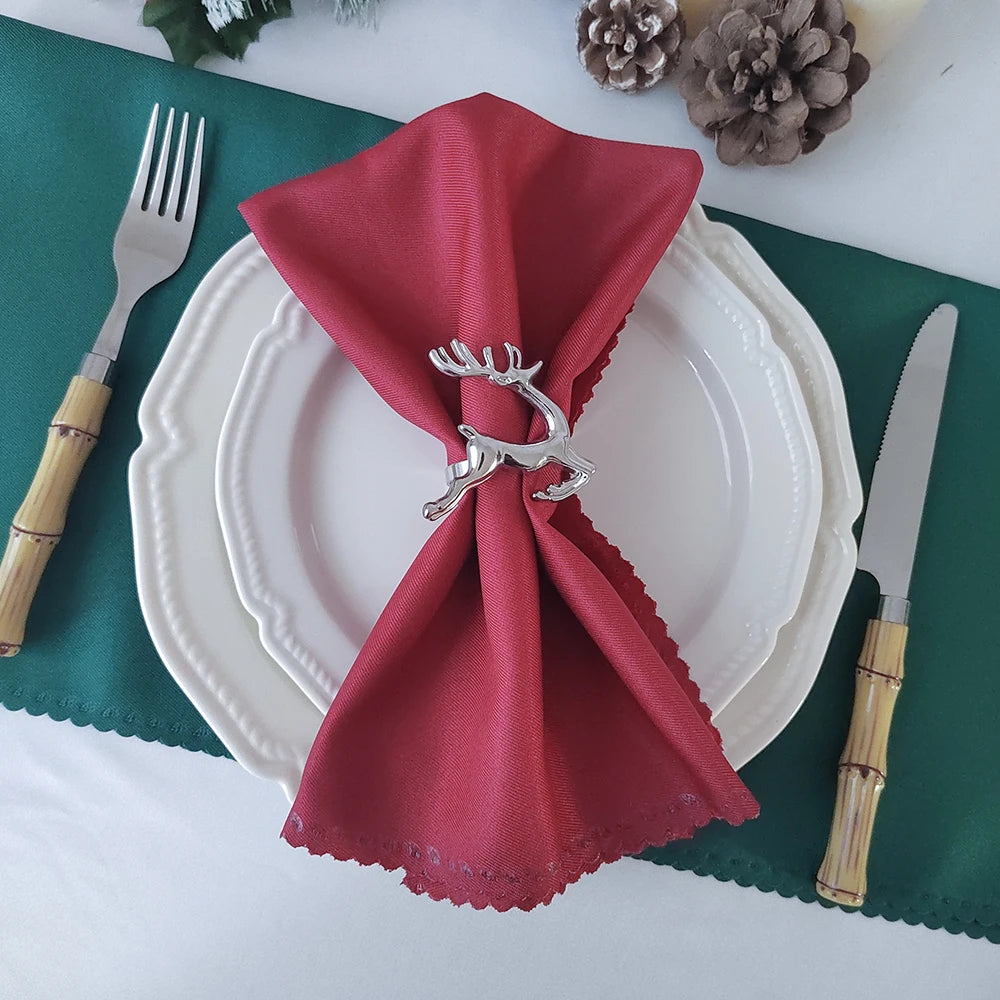 Élégante décoration de table avec serviette rouge festive et décorations de Noël en arrière-plan.