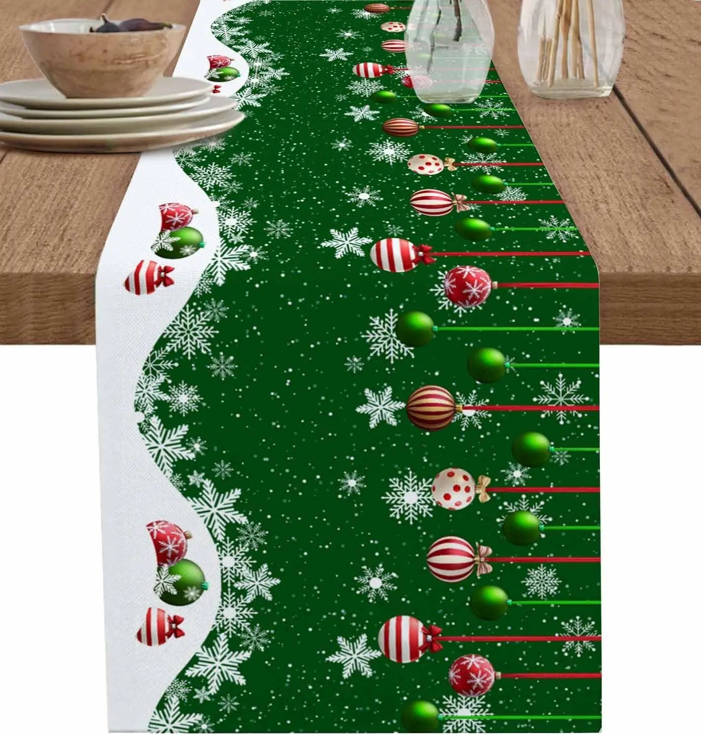 Cette image représente un chemin de table décoré pour Noël avec des boules de Noël rouges et vertes, des flocons de neige et des motifs festifs sur un fond vert.
