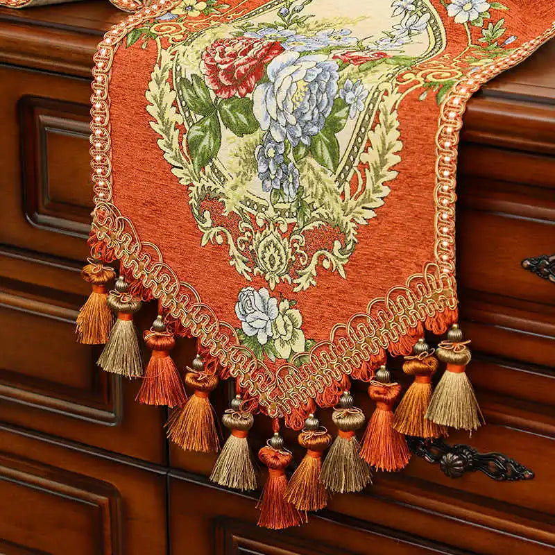 Un magnifique chemin de table orné de motifs floraux colorés et de pompons décoratifs, créant une atmosphère chaleureuse et élégante.