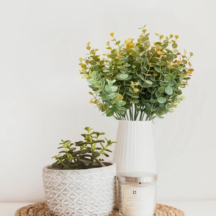 bouquet artificiel feuilles rondes vase blanc plante verte pot bougie blanche papier journal moderne