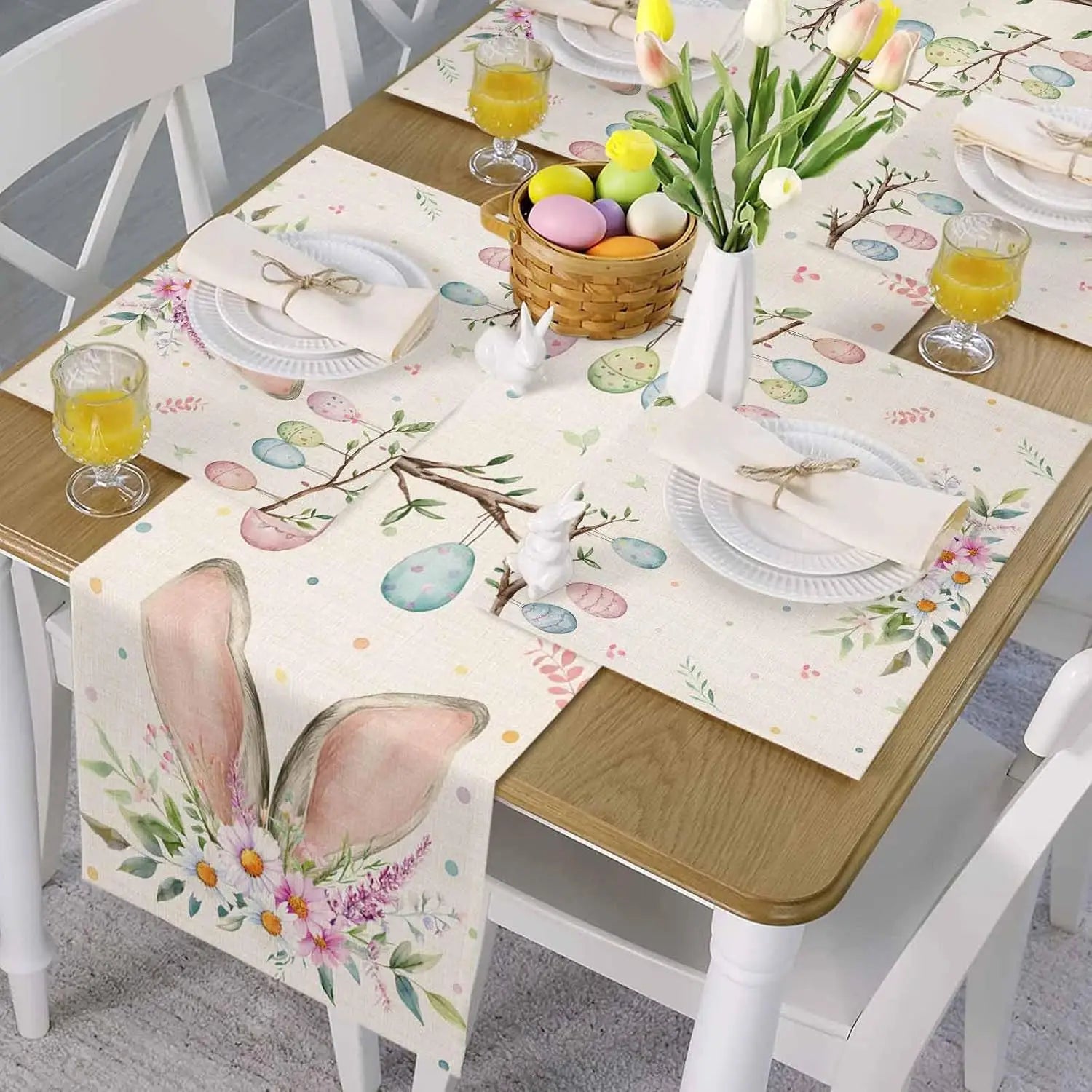 Composition élégante de table de Pâques avec des décorations florales, des œufs colorés dans un panier en osier et des verres remplis de jus d'orange.