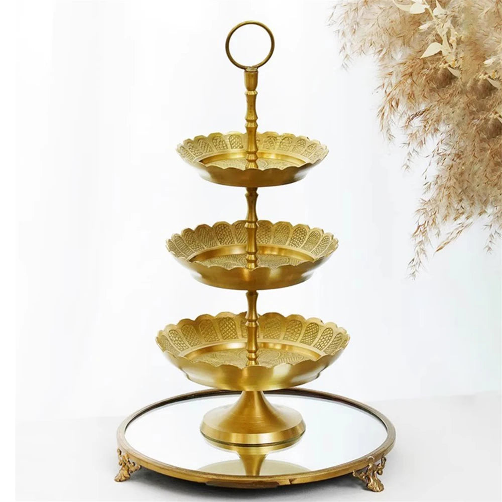 Un présentoir en métal doré à trois niveaux orné de motifs floraux délicats, créant un plateau élégant pour présenter des desserts, des gâteaux ou des collations.