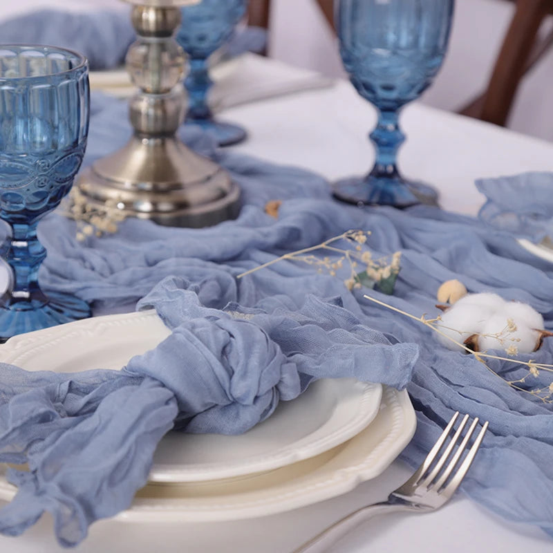 La table est élégamment dressée avec une nappe bleue, des verres en cristal et des accessoires dorés, créant une ambiance chaleureuse et raffinée.