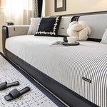 L'image montre un lit avec un cadre rayé noir et blanc, des coussins décoratifs et une tasse de café sur un plateau à côté du lit, avec des sandales noires au sol.