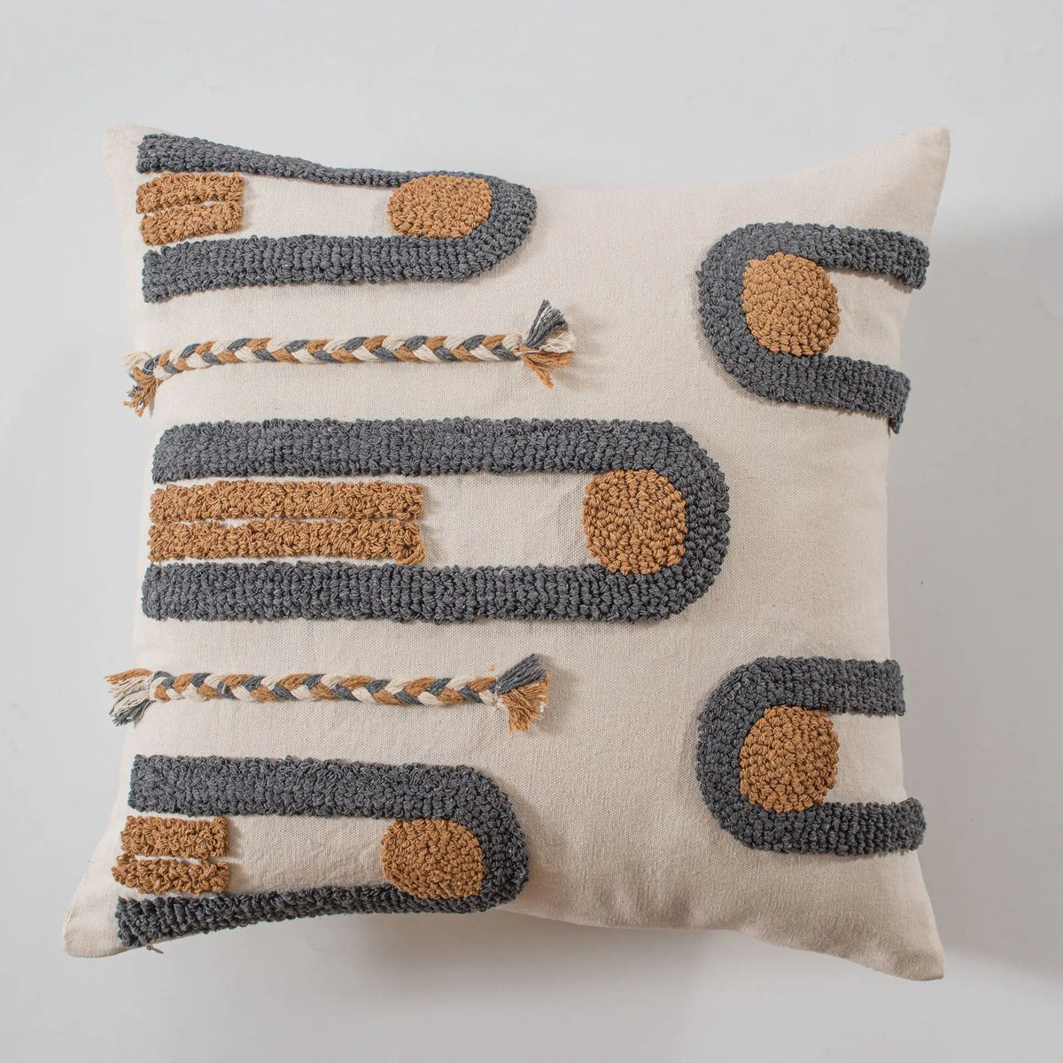Ce coussin décoratif en laine présente un motif géométrique aux couleurs neutres, avec des détails en tressage et des formes arrondies, offrant une touche sophistiquée et moderne à l'espace.