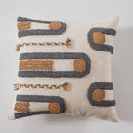 Ce coussin décoratif en laine présente un motif géométrique aux couleurs neutres, avec des détails en tressage et des formes arrondies, offrant une touche sophistiquée et moderne à l'espace.