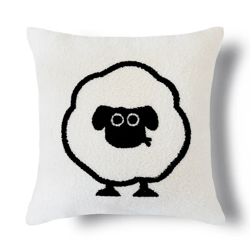 Un coussin blanc décoratif avec une forme de mouton stylisée en noir.
