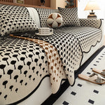 Parure de lit en noir et blanc avec un motif de fleurs et de formes abstraites, composée d'un couvre-lit, de coussins et d'éléments décoratifs, créant une ambiance élégante et chaleureuse dans la chambre.