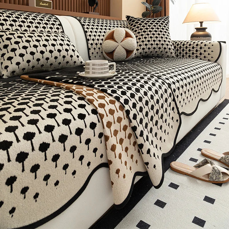 Parure de lit en noir et blanc avec un motif de fleurs et de formes abstraites, composée d'un couvre-lit, de coussins et d'éléments décoratifs, créant une ambiance élégante et chaleureuse dans la chambre.