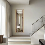 Un élégant miroir doré encadre un coin de la pièce, reflétant la lumière naturelle qui filtre à travers les rideaux.