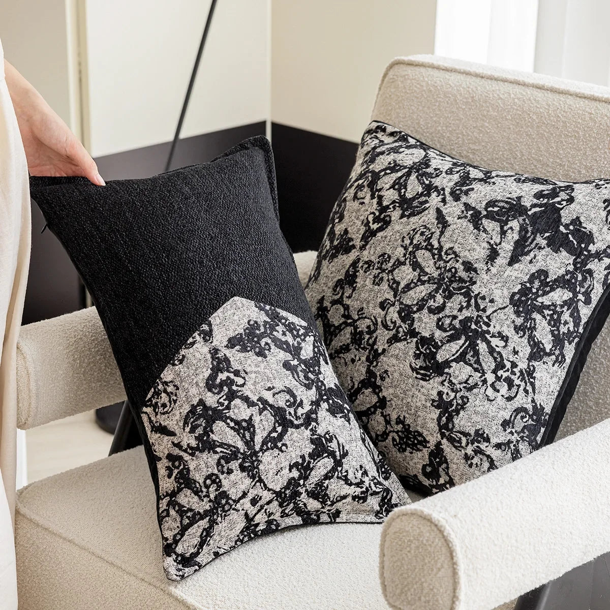 Coussin décoratif avec motif floral monochrome sur un canapé beige, créant une ambiance élégante et apaisante dans l'espace.