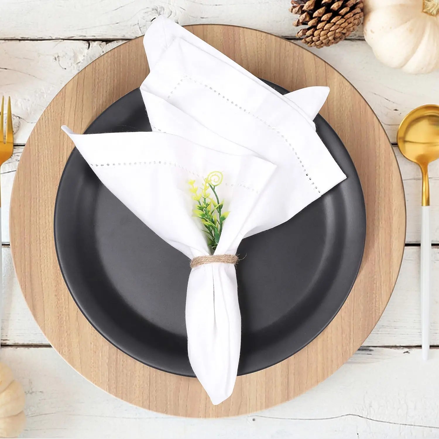 Une mise en place élégante avec des assiettes noires, des serviettes blanches et une décoration florale.