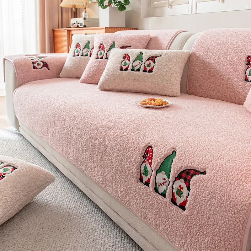 Cette image montre un canapé rose, avec des coussins décorés de motifs de lutins de Noël. Le canapé est placé dans un environnement confortable et cosy, avec des éléments de décoration qui apportent une touche festive à la pièce.
