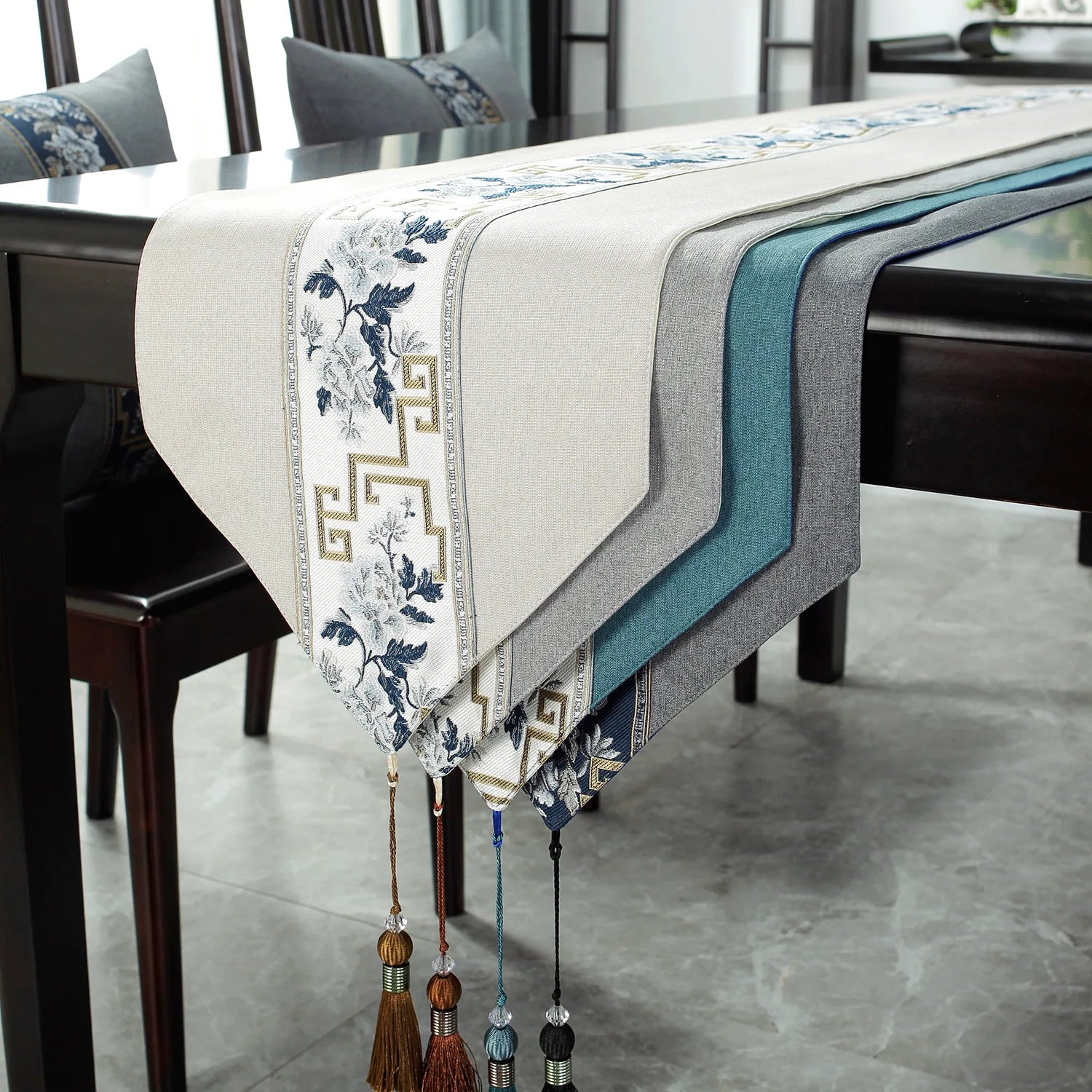 Chemin de table orné de motifs floraux bleus et d'un motif grec doré, accompagné de décorations pendantes assorties, créant une ambiance élégante et raffinée dans cette salle à manger.